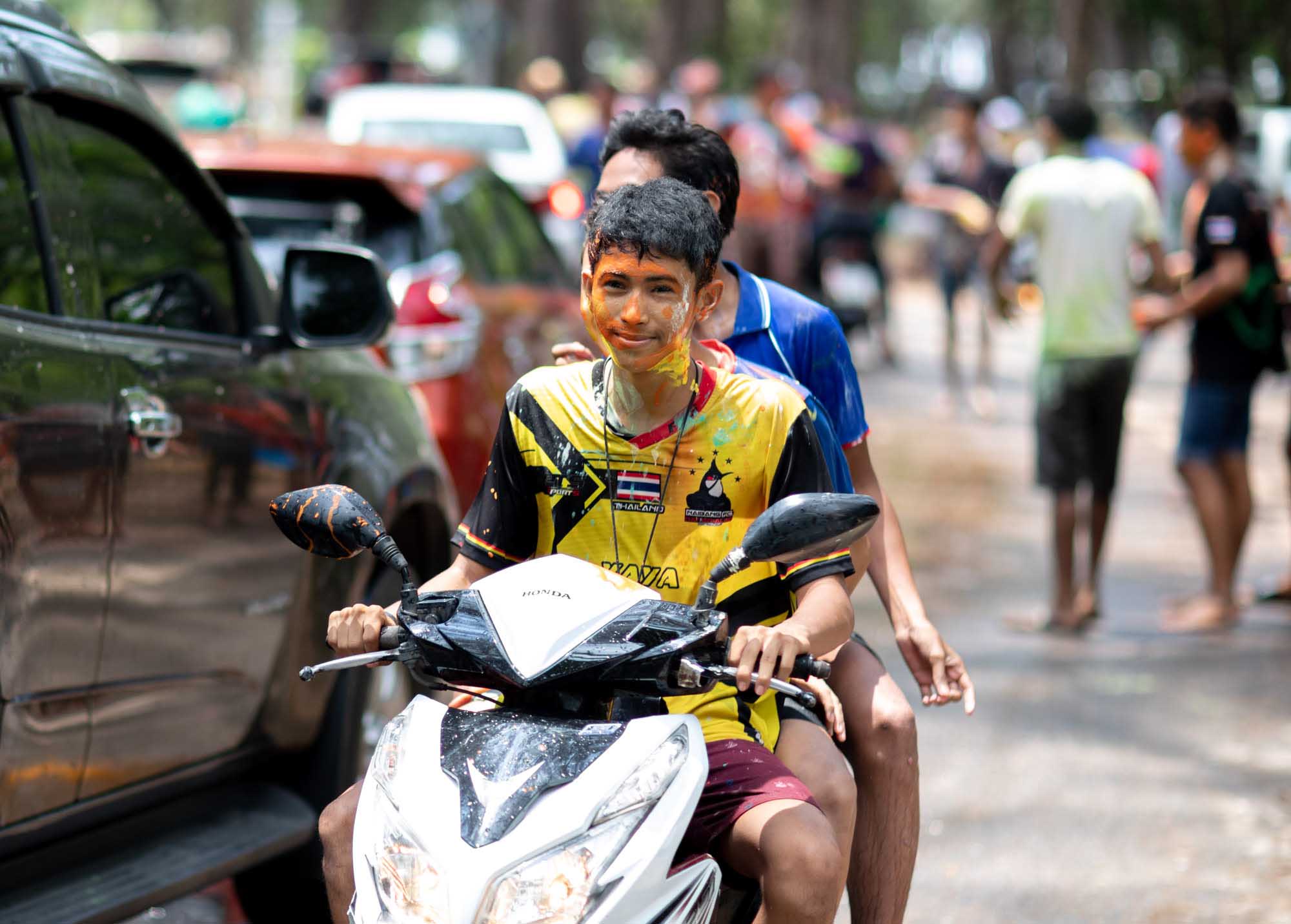 Two boys on a motorbike with painted faces during Songkran water festival in Phuket, Thailand