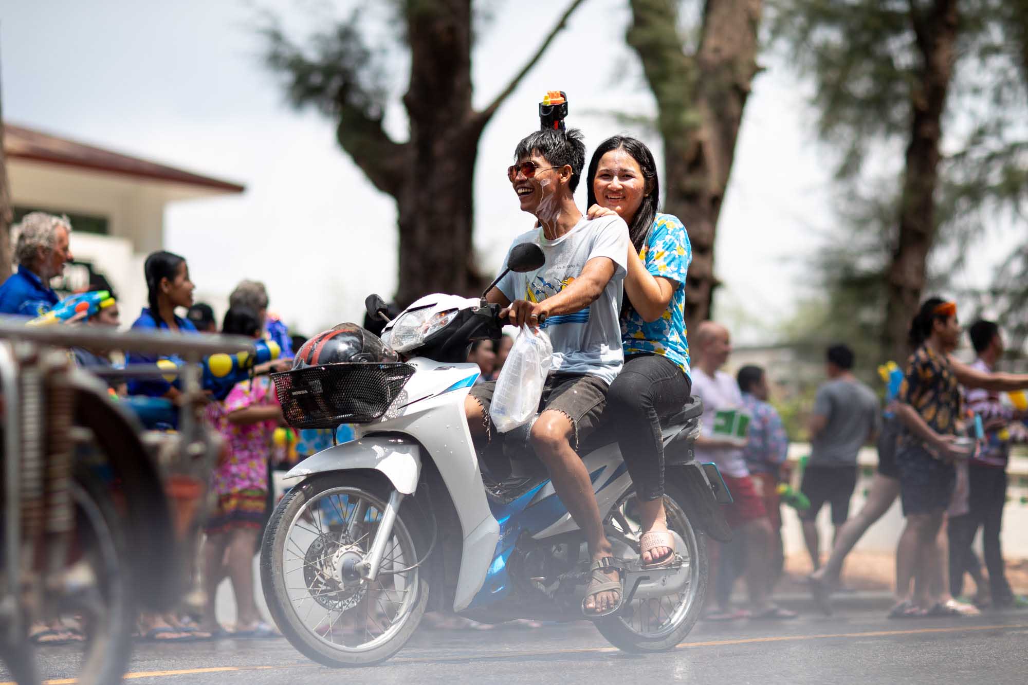 Smiling man and woman on motorbike at Songkran water festival in Phuket, Thailand