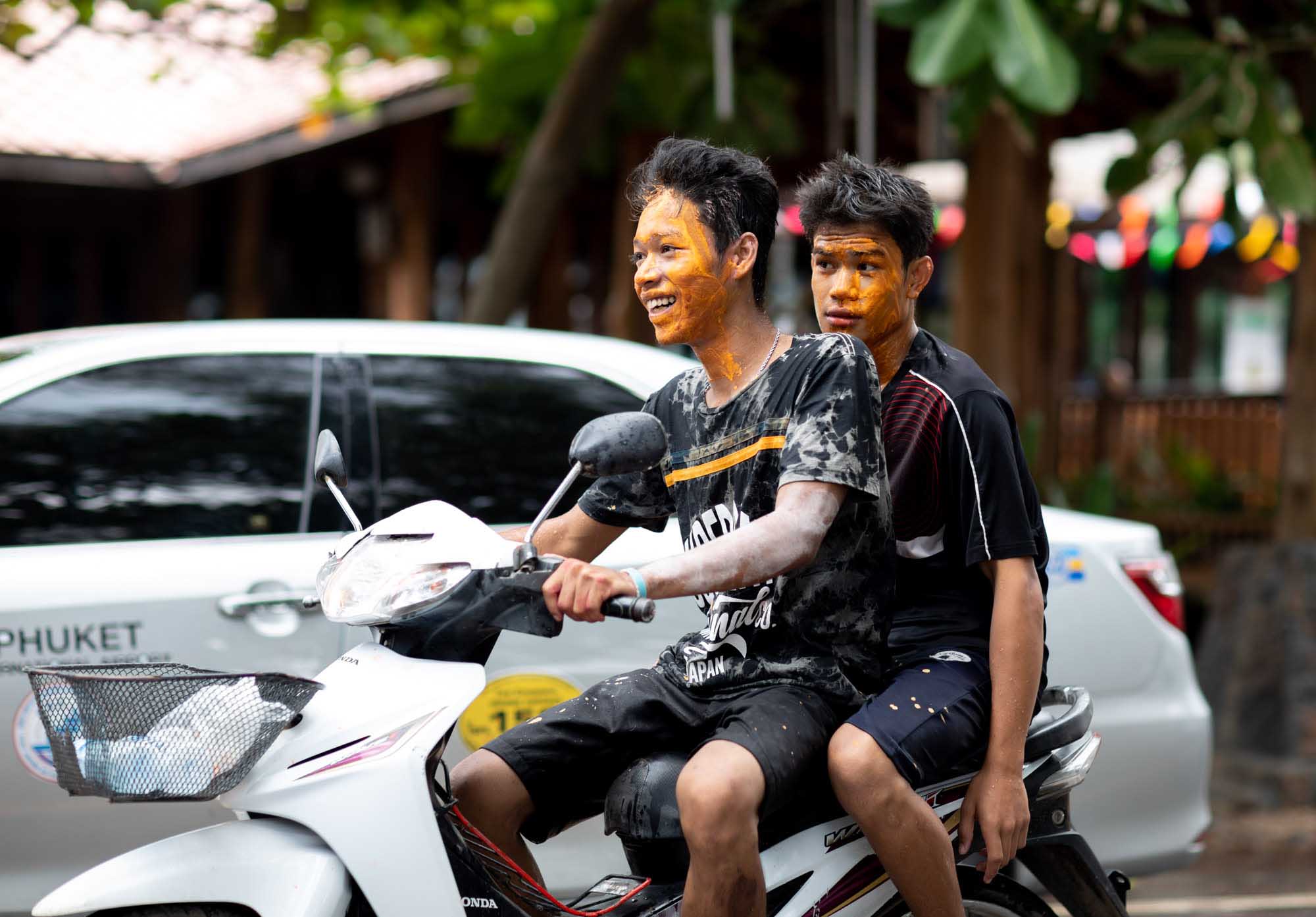 Two boys with orange paint on their faces at Songkran water festival in Phuket, Thailand