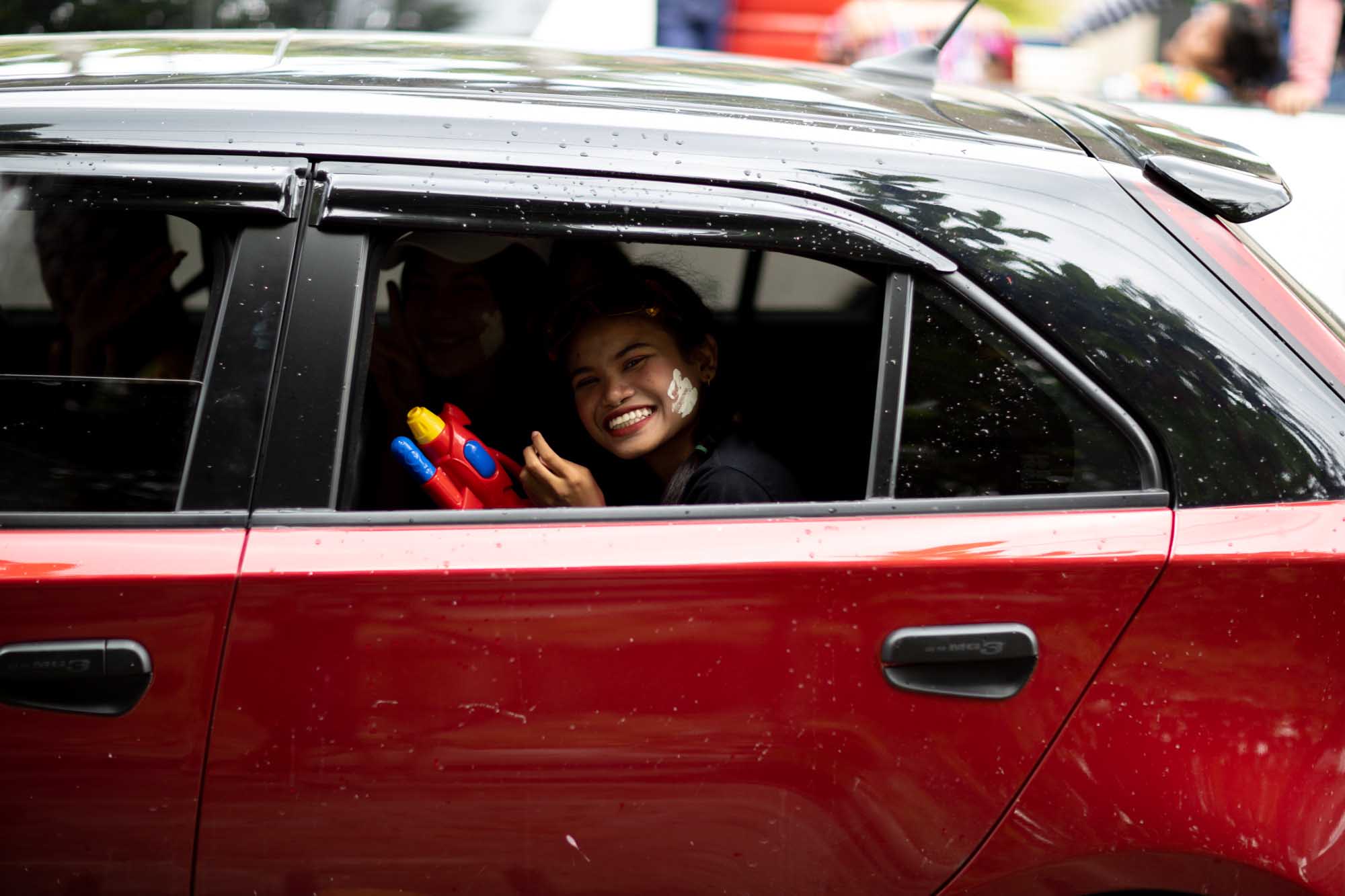 Happy woman in back seat of car during Songkran water festival in Phuket, Thailand