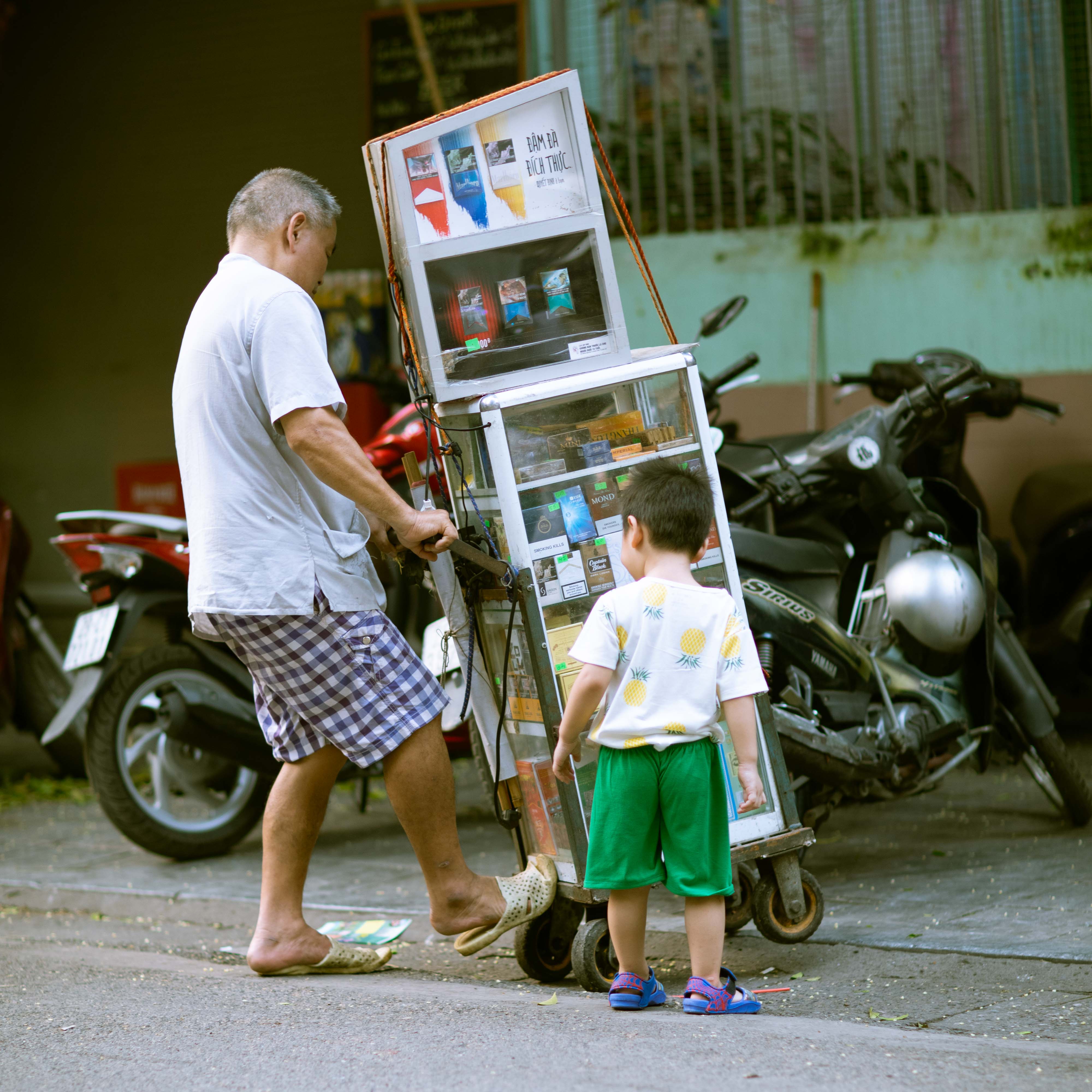 Street Photography of man moving a cart along with a small child on the streets of Hanoi, Vietnam | Travel Photography