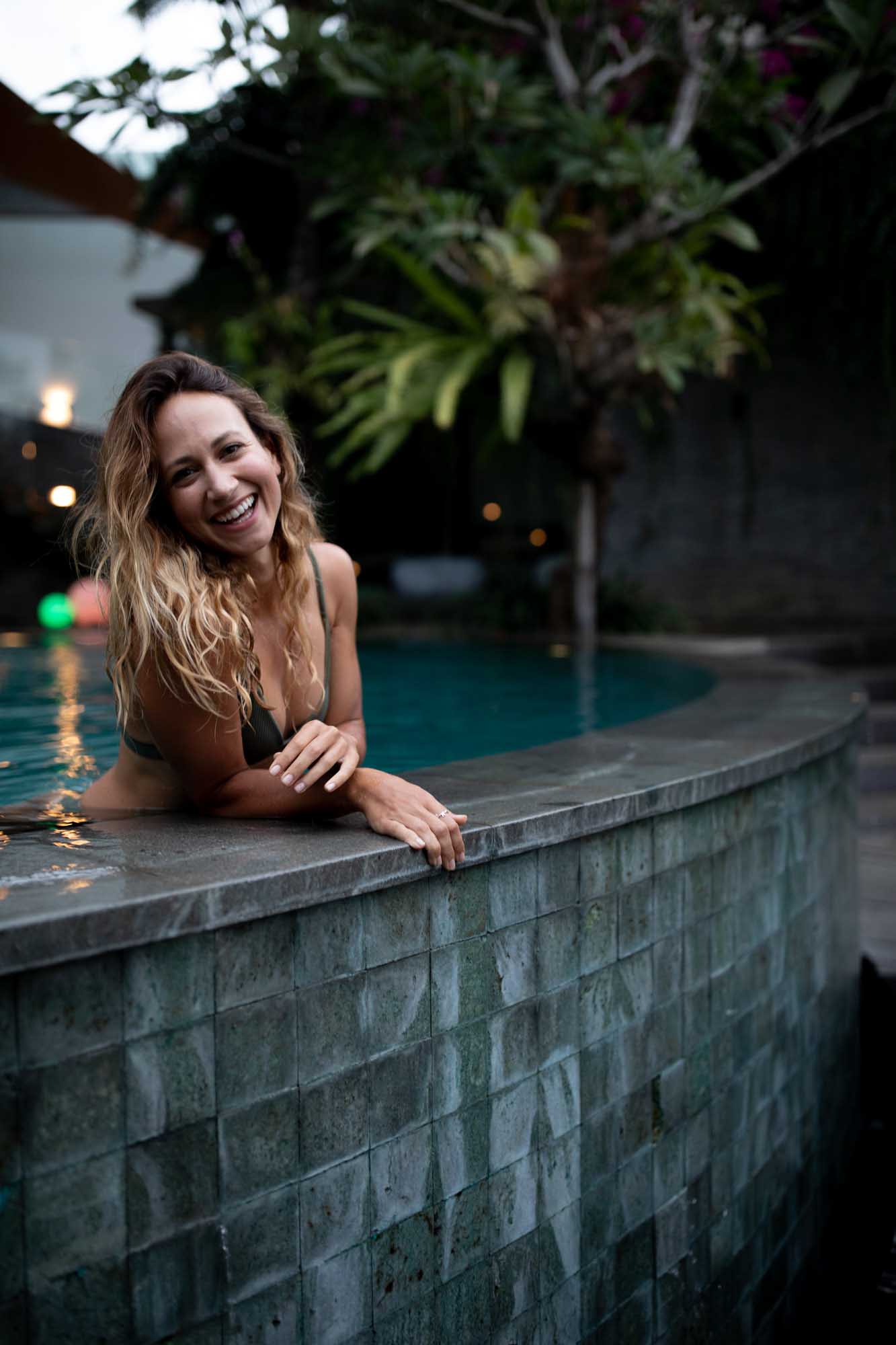 Beautiful blonde woman laughs playfully on the edge of an infinity pool in green bikini | Canggu Bali Indonesia | Toraja Villa | Lifestyle Photography | Fashion Photography | Travel Photography | Swimwear Photography 