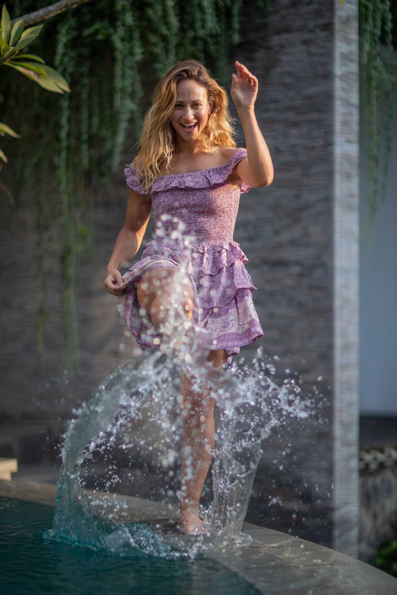 Beautiful blonde woman playfully kicks water at the camer on the edge of pool | Canggu Bali Indonesia | Toraja Villa | Lifestyle Photography | Fashion Photography | Travel Photography 