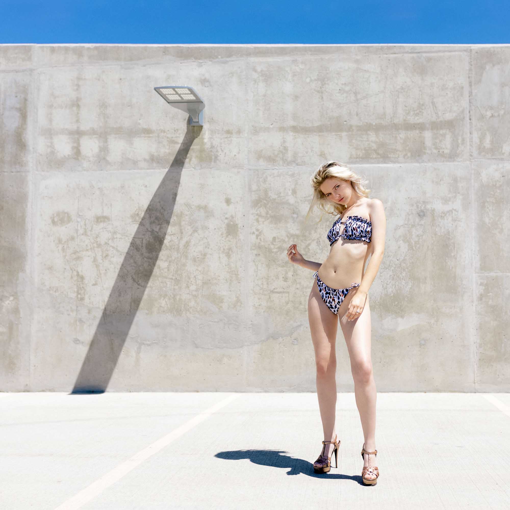 Model in bikini swimwear poses in parking lot with dramatic light and shadow | Meghan Travers @traversmeghan | Teen Model | Fashion Photography | Denver, Colorado
